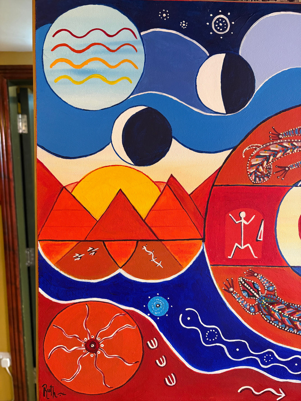 Left-side painting detail showing red triangles, yellow sun shapes, crescent moons and wavy lines.