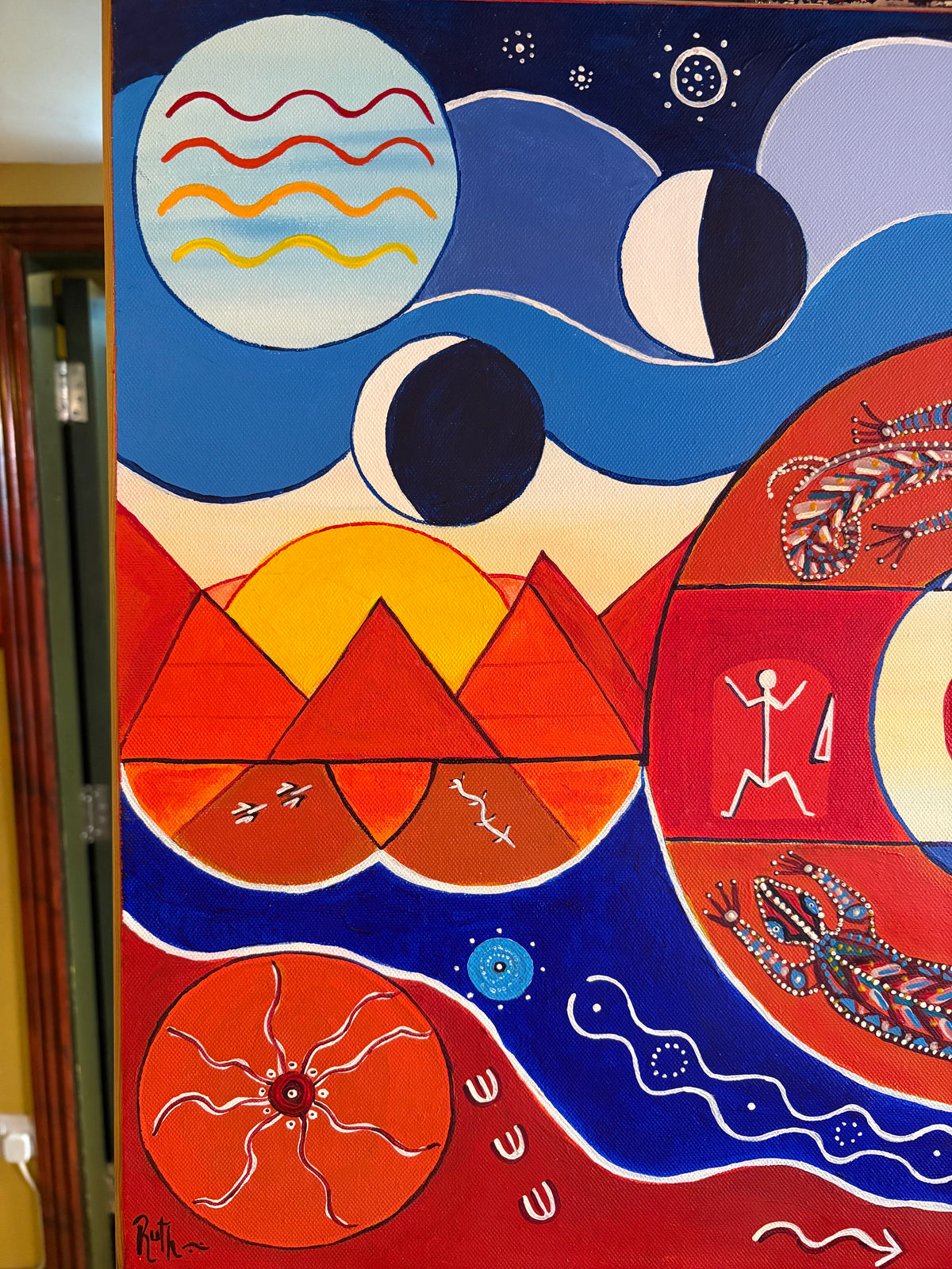Left-side painting detail showing red triangles, yellow sun shapes, crescent moons and wavy lines.