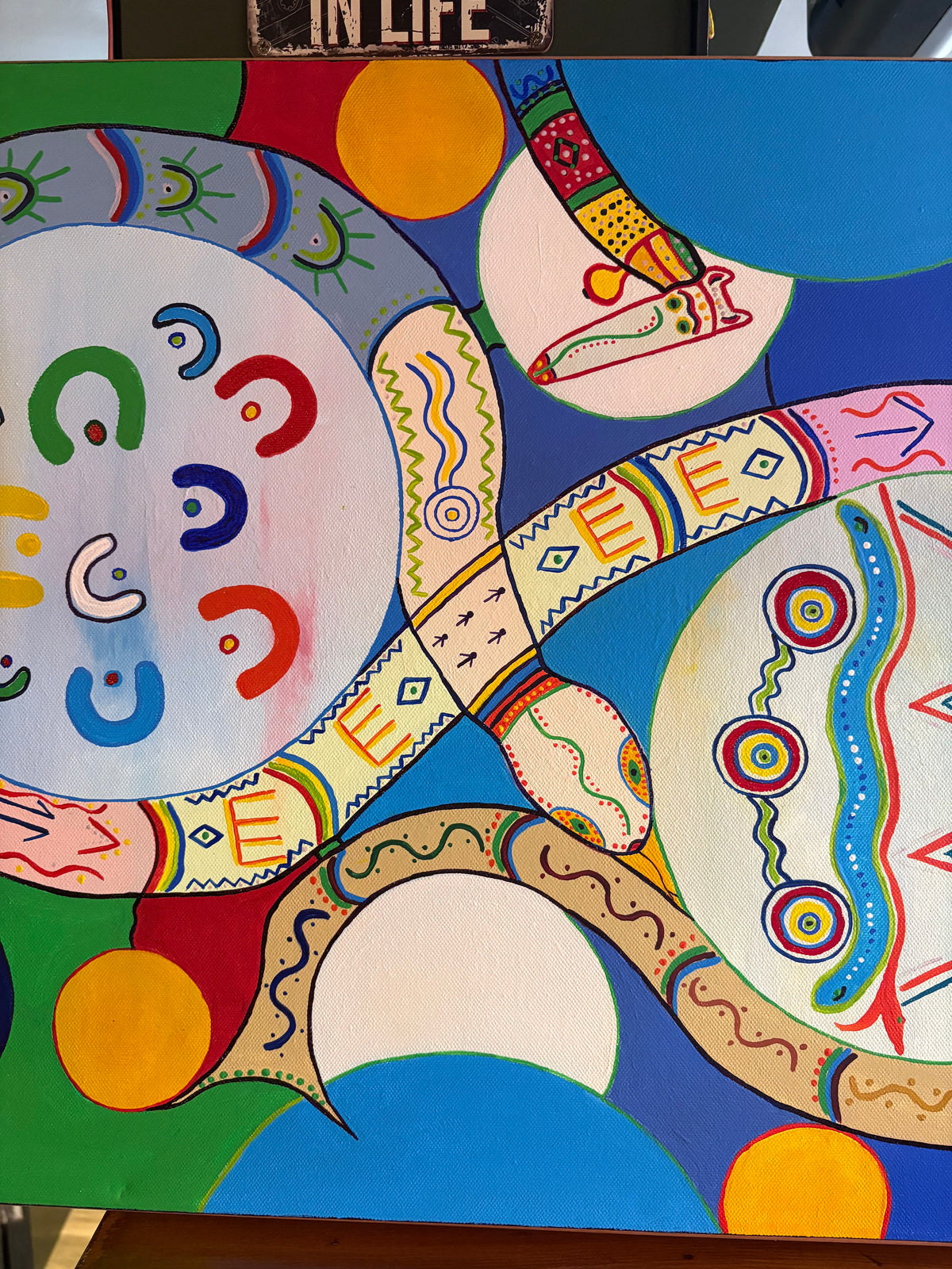Central abstract painting detail showing intersecting patterned bands, curved shapes and colourful circles.