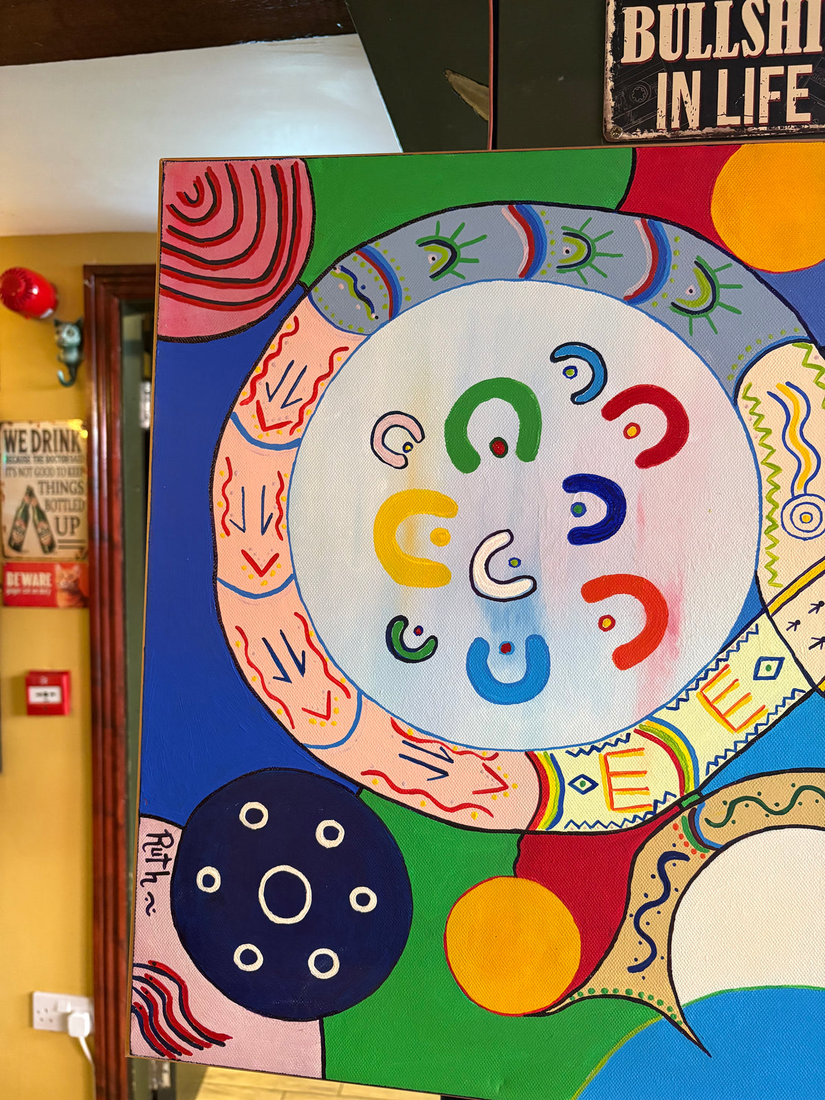 Left-side abstract painting detail showing colourful U-shaped motifs within a large patterned circle.