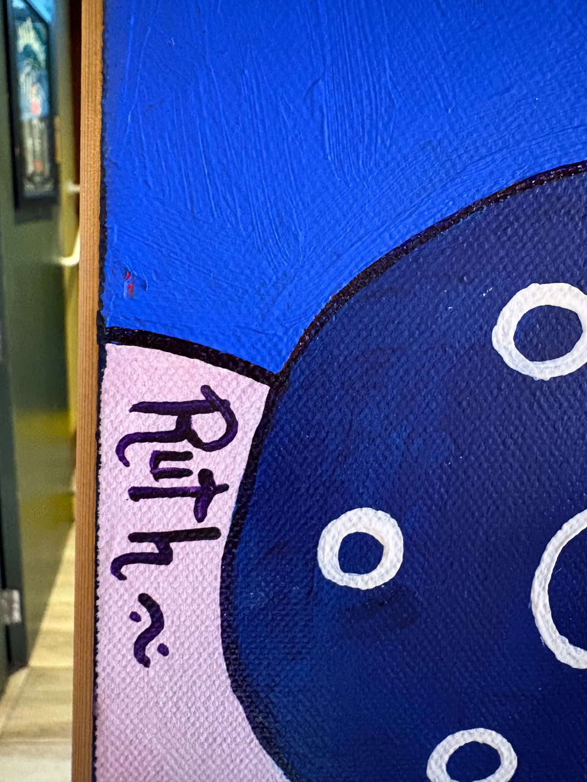 Close-up of the Ruth signature beside a dark blue circle and textured blue paint.