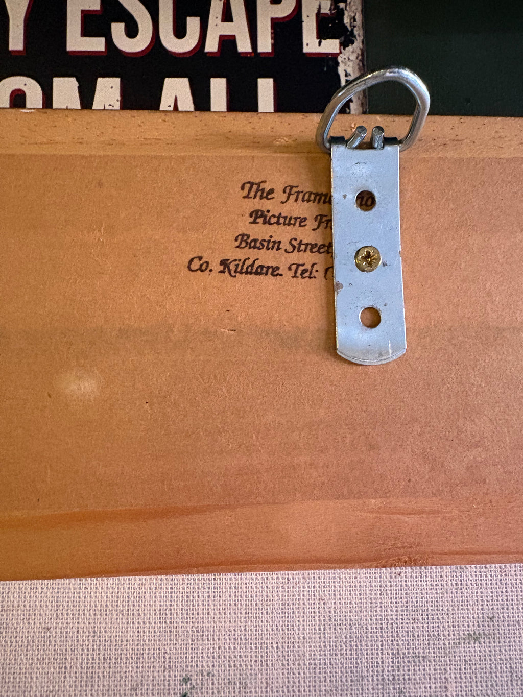 Reverse detail of the clown picture showing a metal hanging bracket and picture-framer stamp.