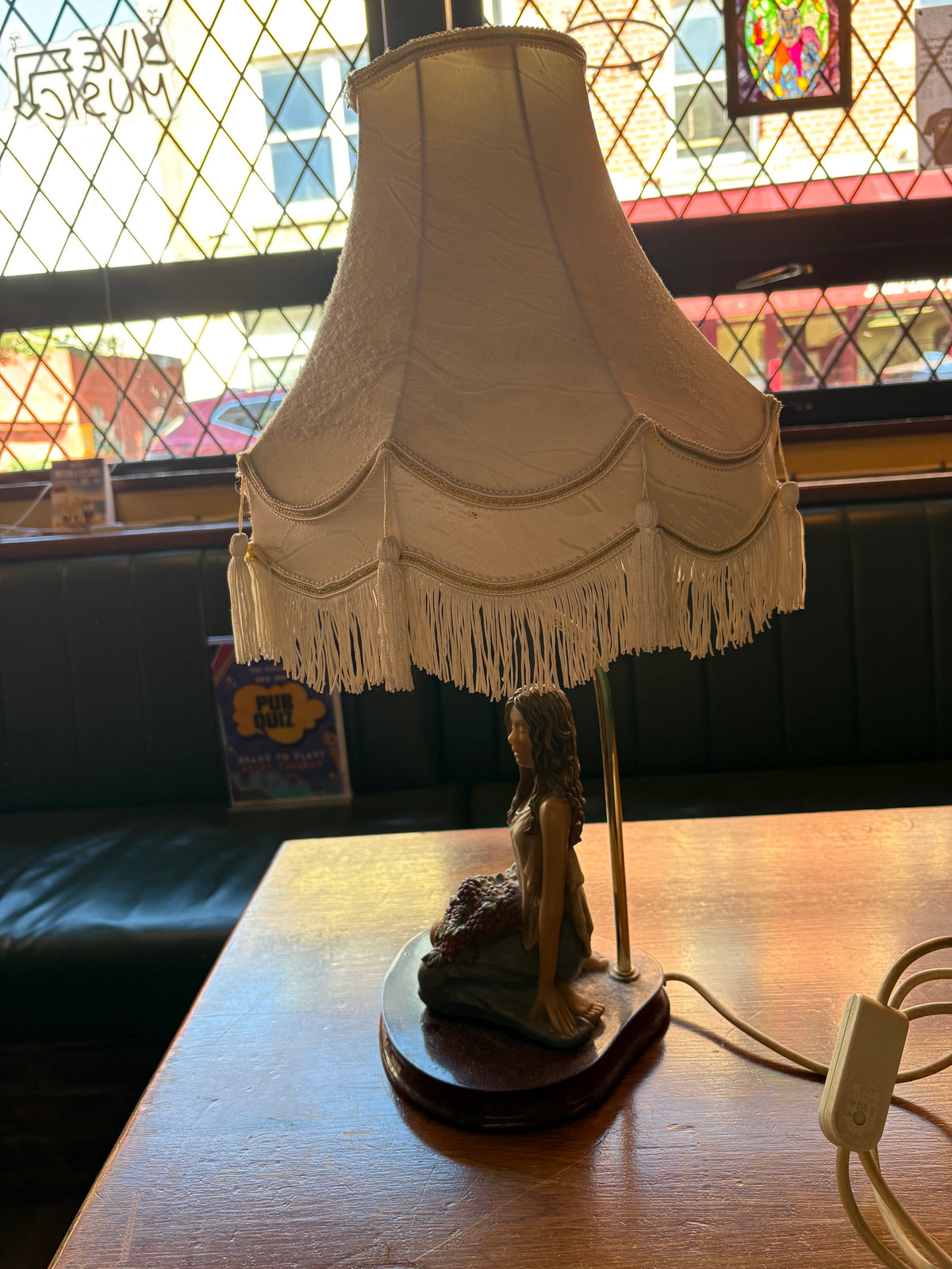 Opposite side of figural table lamp showing the woman, oval base and fringed cream shade