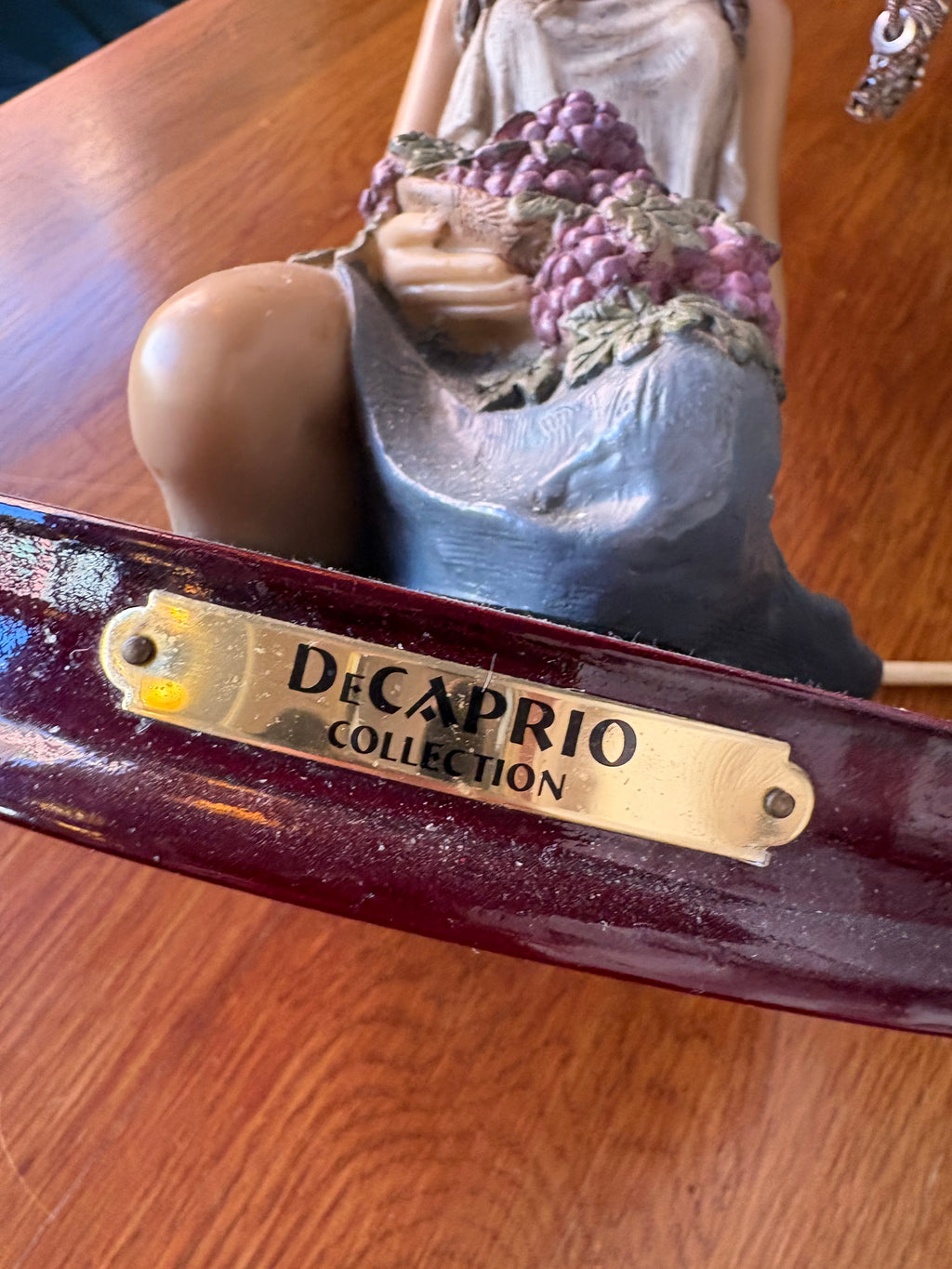 Close-up of Decaprio Collection plaque on the figural lamp base beneath the grape-holding woman