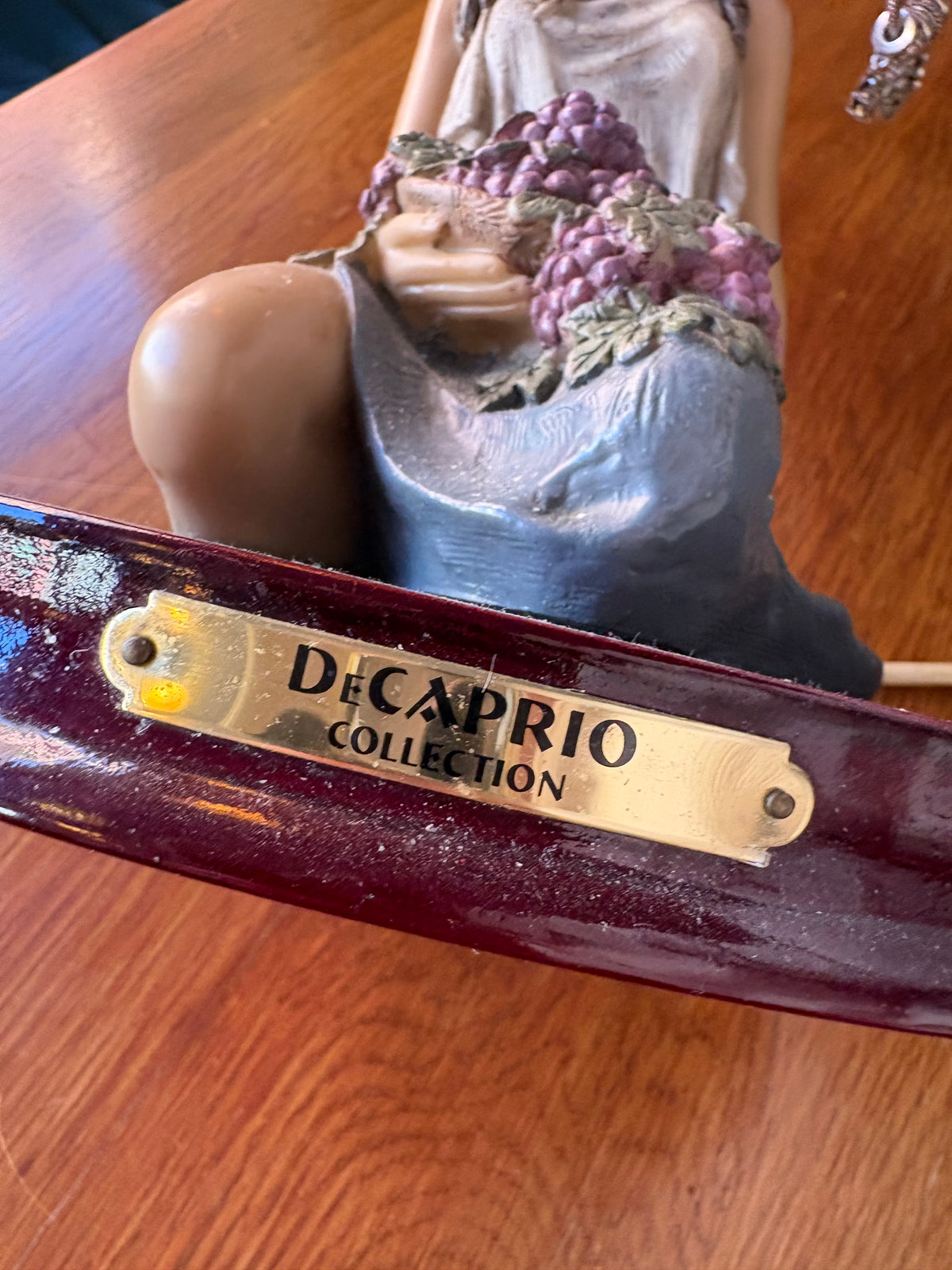 Close-up of Decaprio Collection plaque on the figural lamp base beneath the grape-holding woman