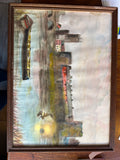 Framed riverside town picture photographed sideways, with stone towers, colourful houses and boats.