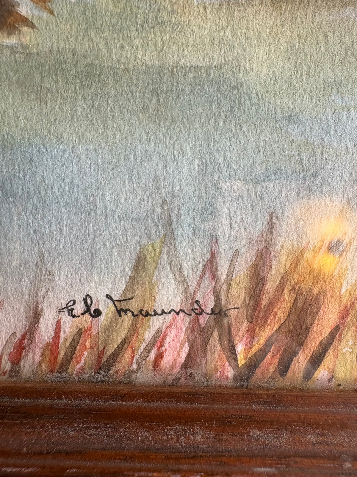 Close-up of the signature above the wooden frame in the riverside town picture.