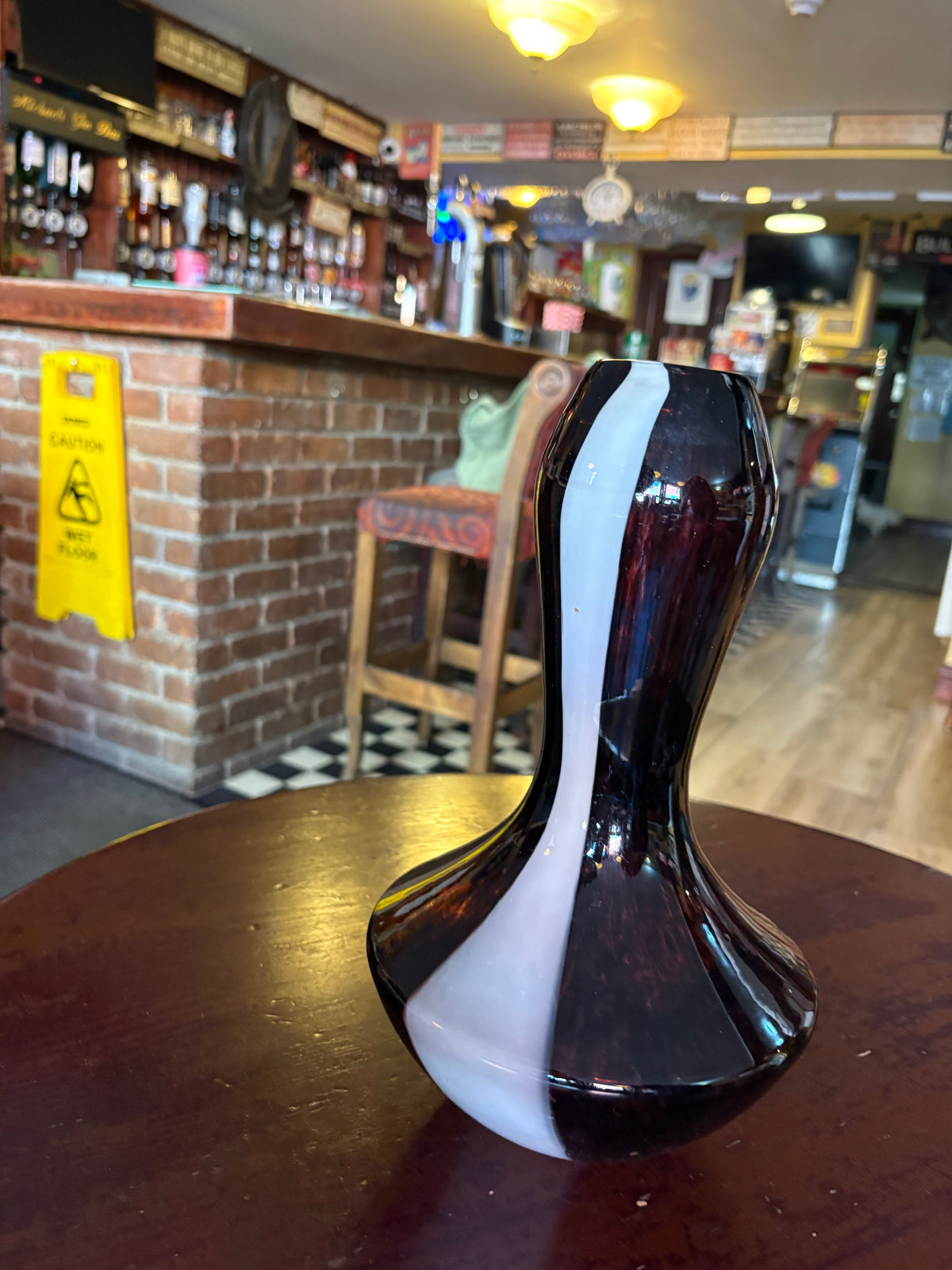 Angled view of purple glass vase showing the curved white stripe from rim to base
