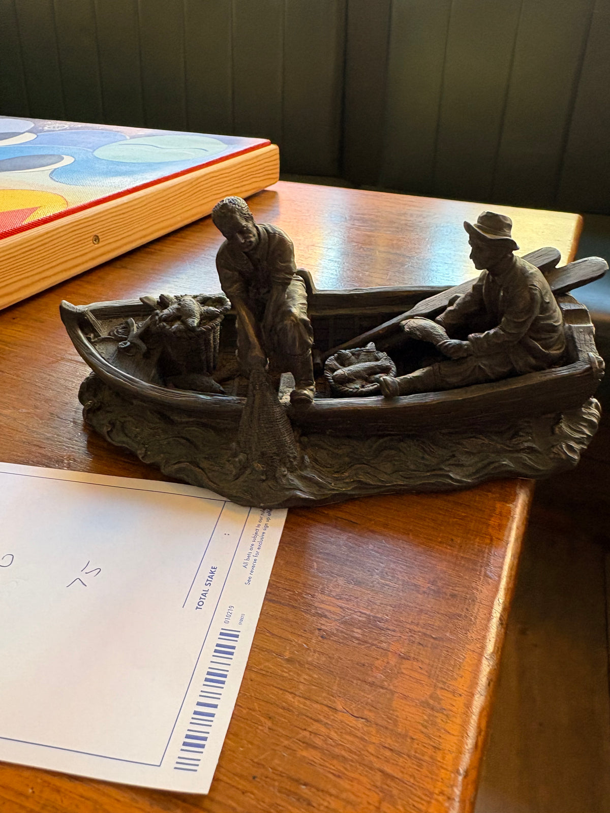 Side view of the fishing boat sculpture showing a fisherman hauling a net and a seated fisherman holding a fish