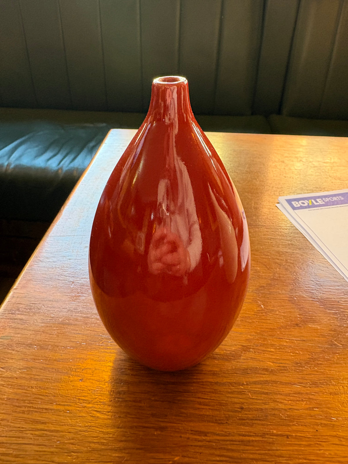 Red teardrop ceramic bud vase with glossy finish and narrow neck