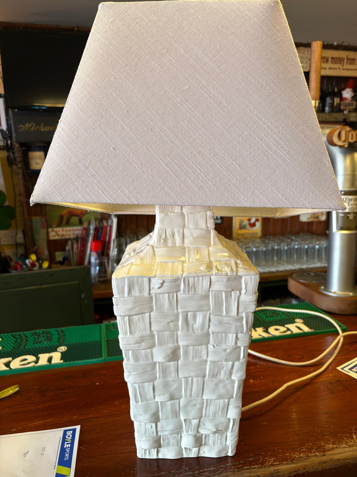 White ceramic table lamp with raised basket-weave texture and a pale rectangular tapered shade