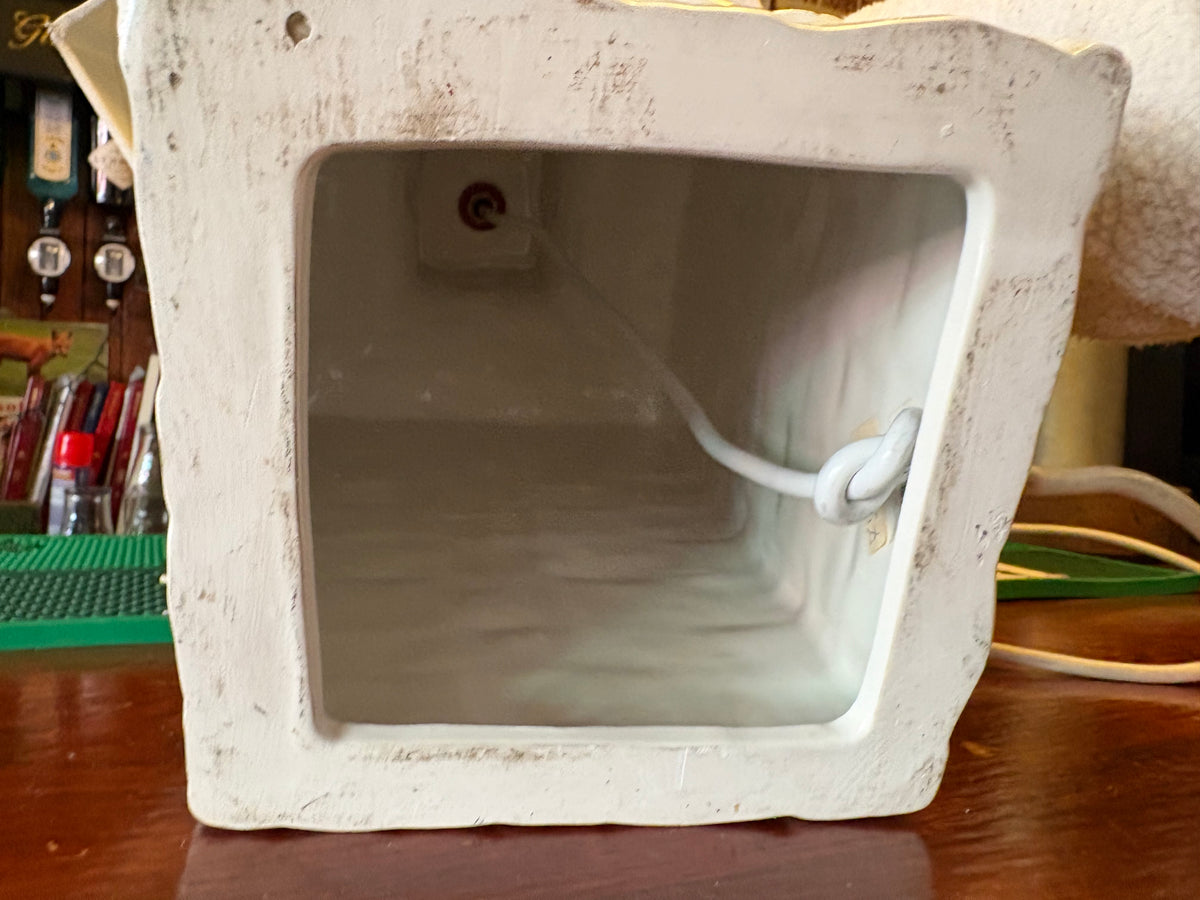 Underside of the white ceramic lamp showing its hollow square base and cord