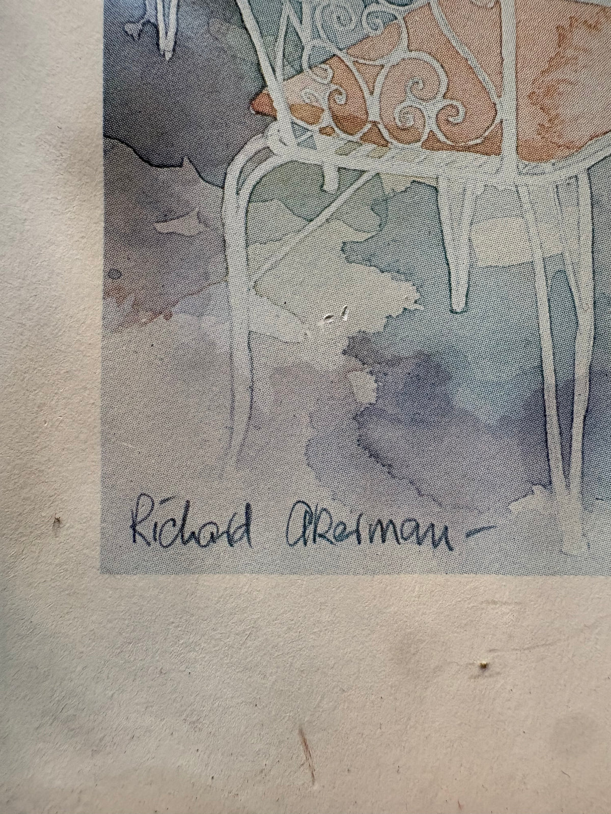 Close-up of the Richard Akerman signature beneath a white garden chair with a peach cushion.