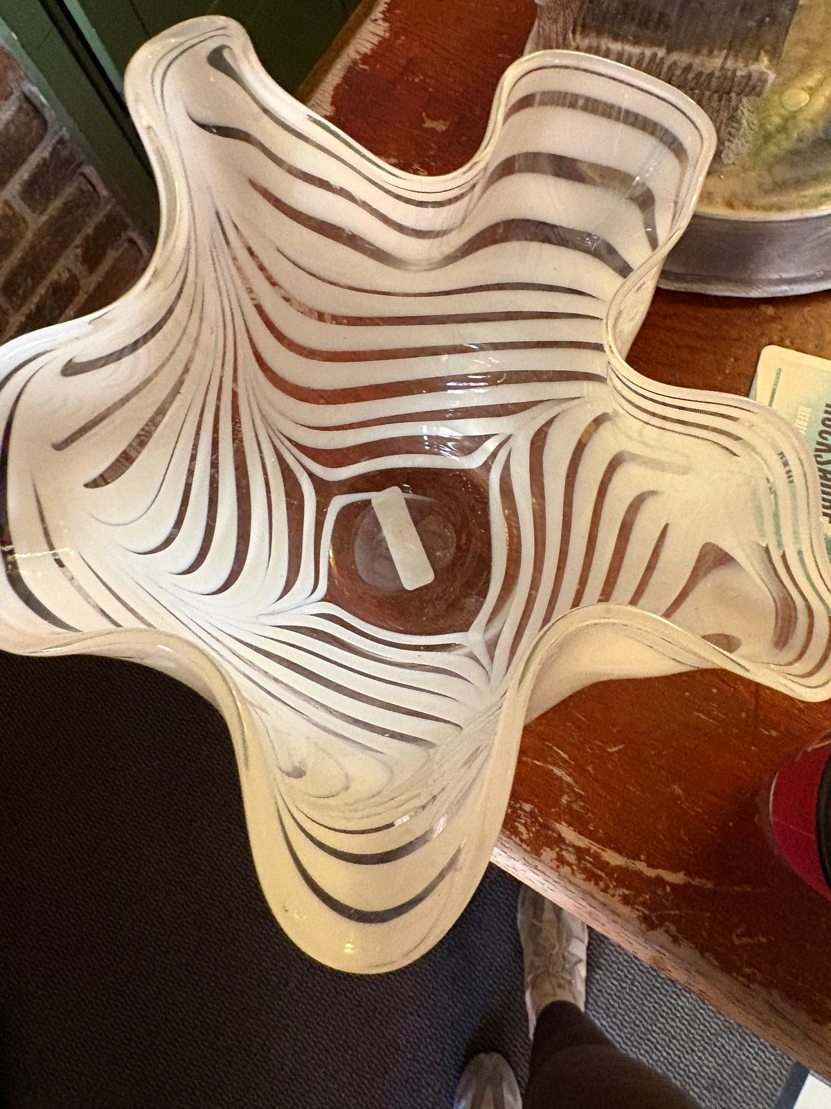 Top view of white-ribbon glass vase showing its deeply folded wavy rim and striped interior