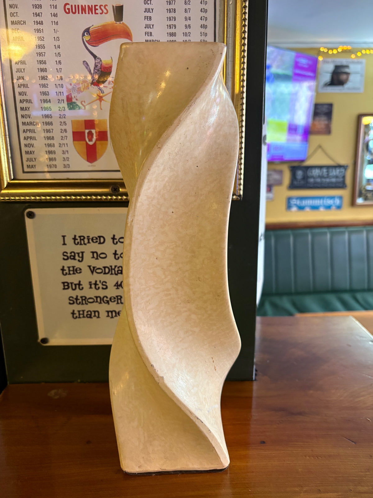 Side view of tall cream twisted vase with a narrow waist and curved outer edges