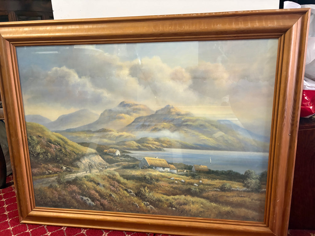 Framed mountain and loch landscape with thatched cottages beside a winding hillside path.