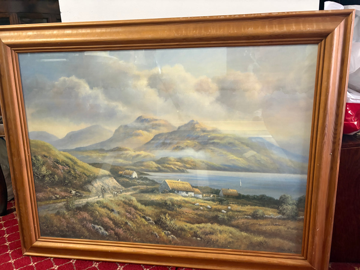 Framed mountain and loch landscape with thatched cottages beside a winding hillside path.
