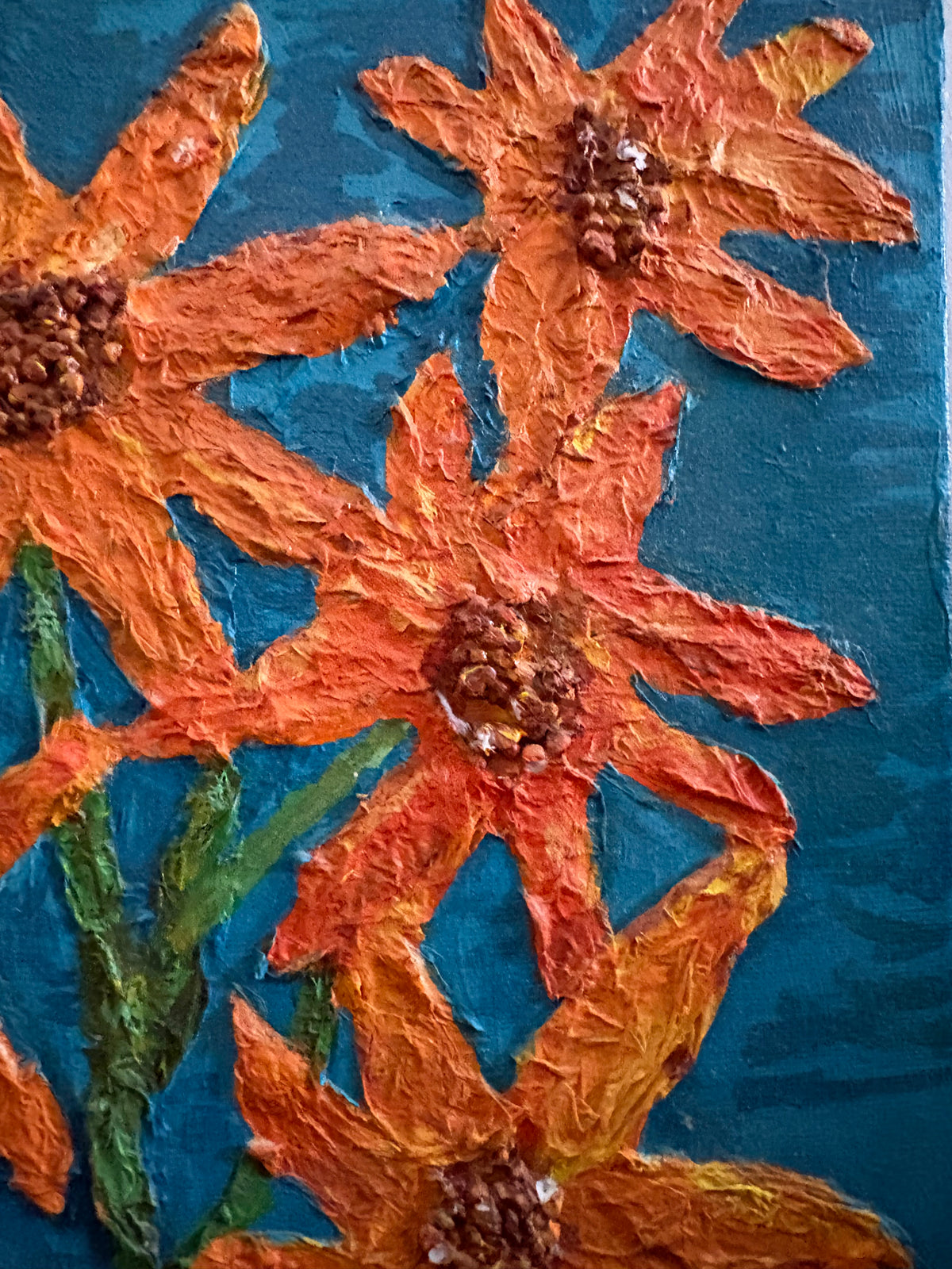 Close-up of orange flower petals and raised brown centres against the teal background.