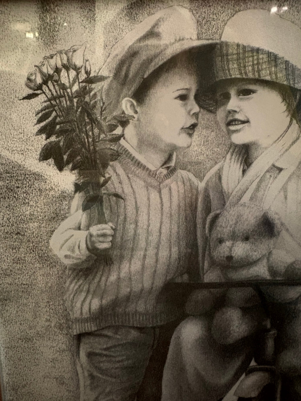 Detail of the child holding a bouquet beside another child and a teddy bear.