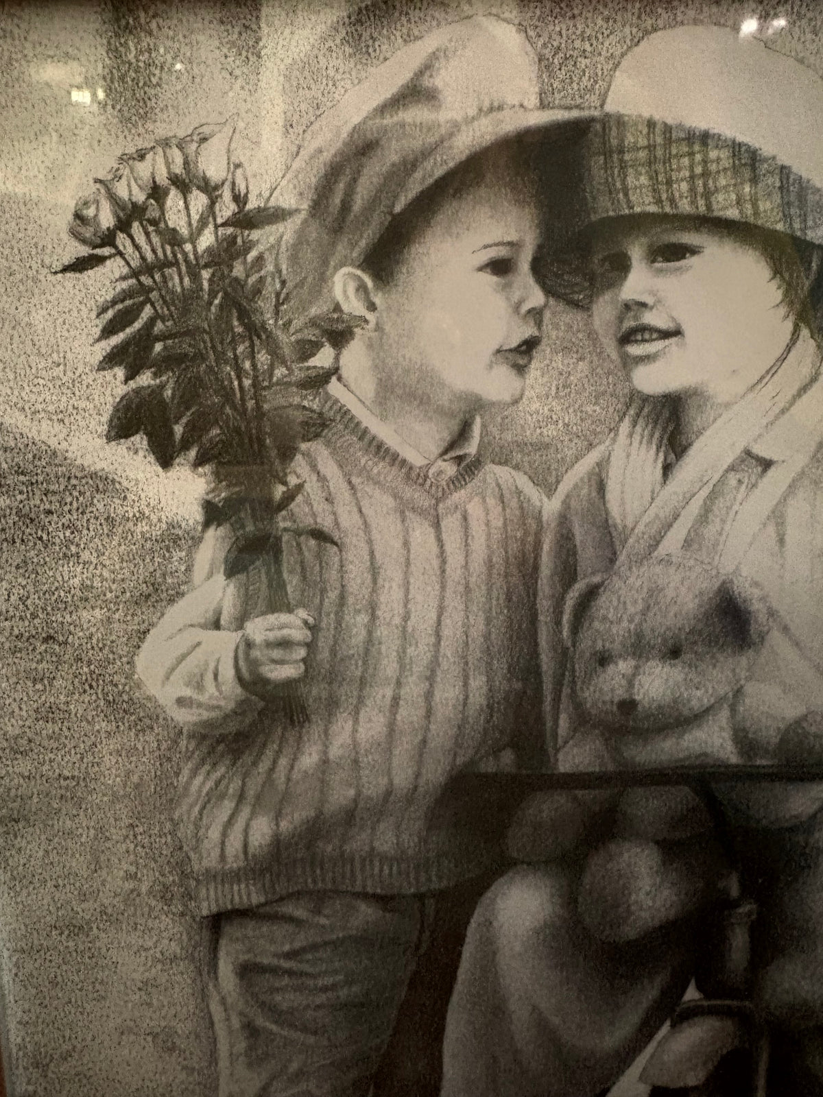 Detail of the child holding a bouquet beside another child and a teddy bear.