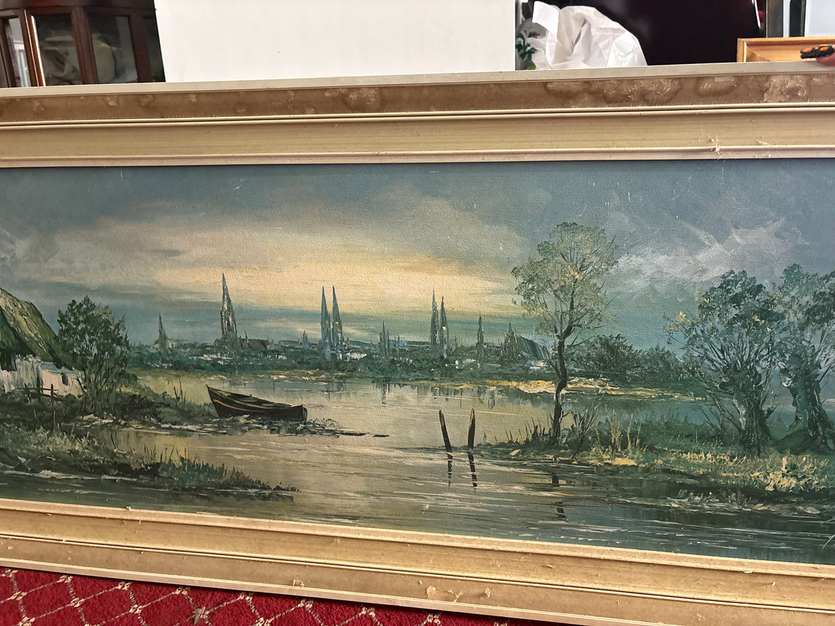 Panoramic river landscape with a boat, cottage and distant church spires in a gold-toned frame.