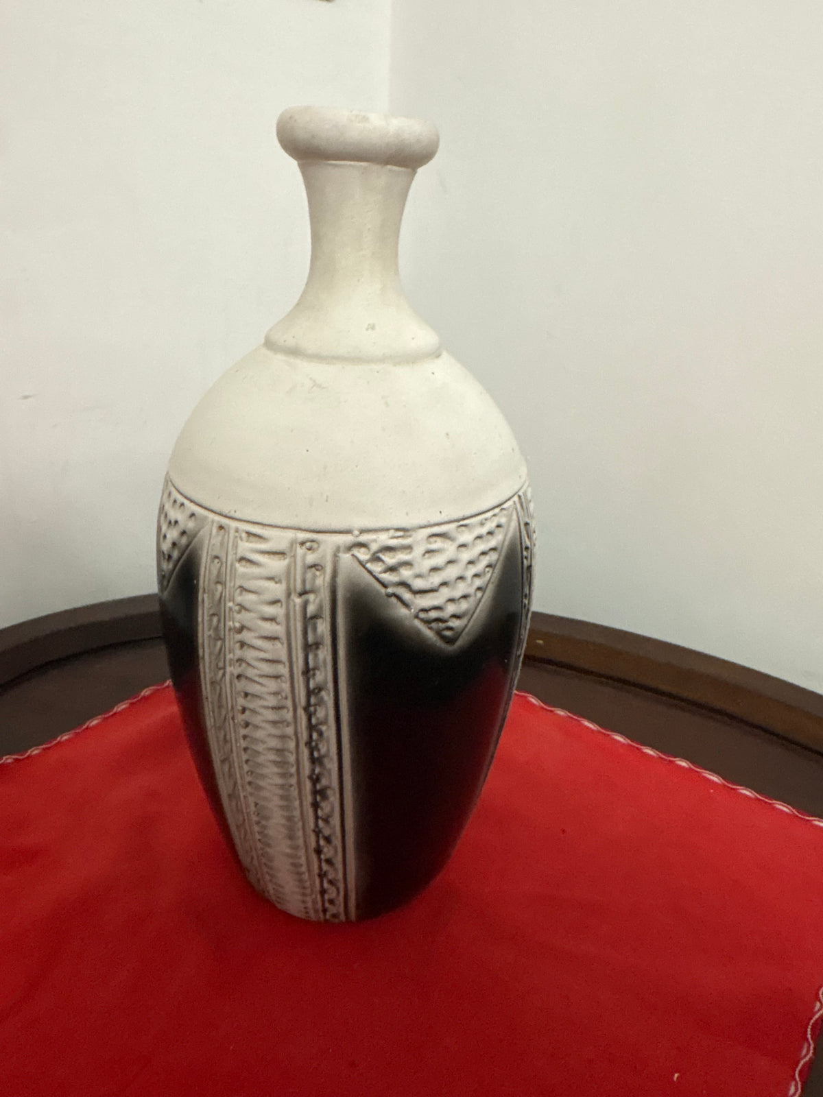 Angled view of cream-and-dark vase showing raised vertical bands and triangular textured decoration