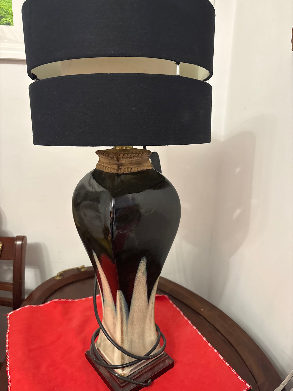 Angled full view of two-tone ceramic lamp with black banded shade and square dark base