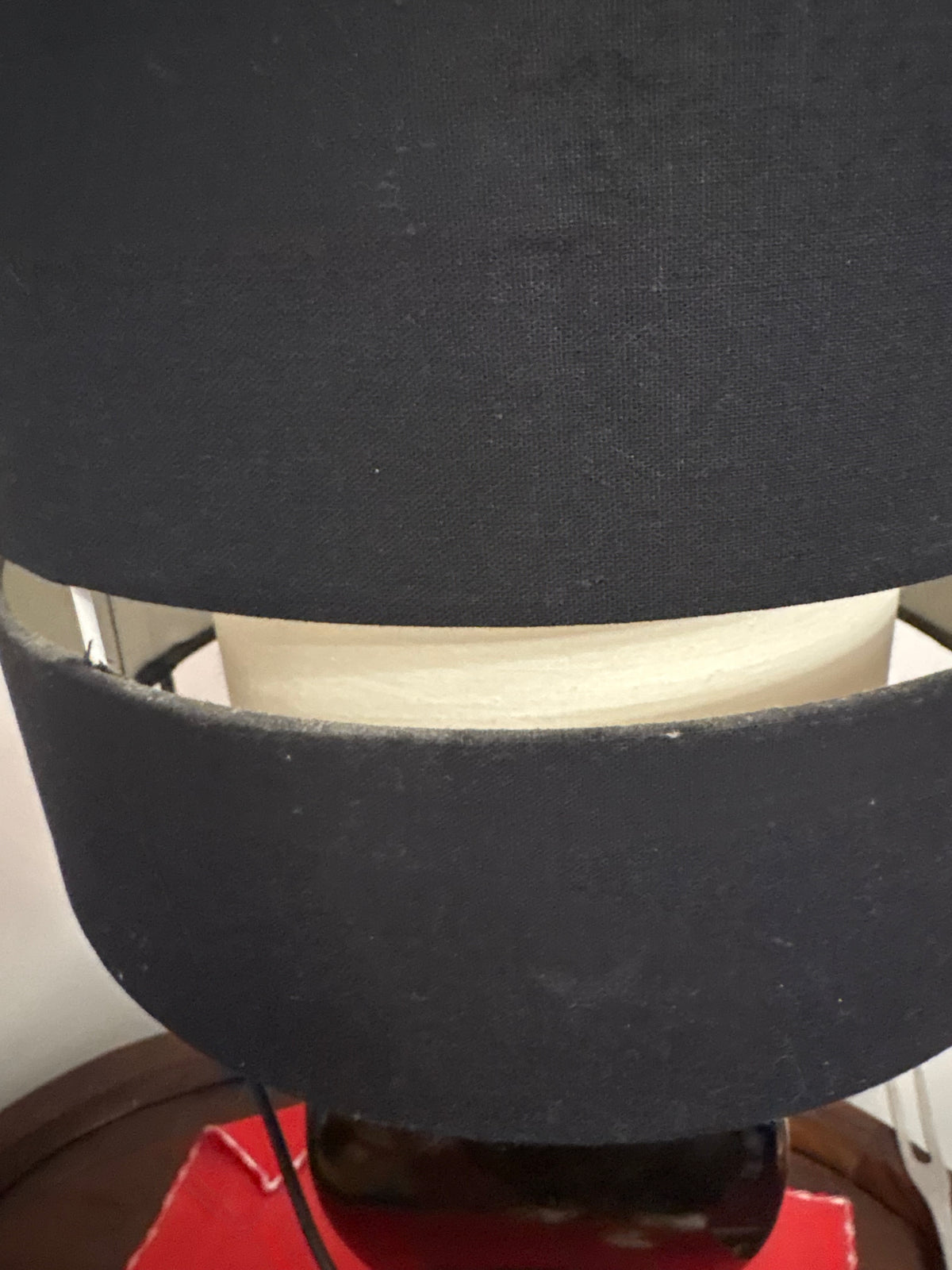 Close-up of black lampshade with a reflective metallic band between two fabric sections
