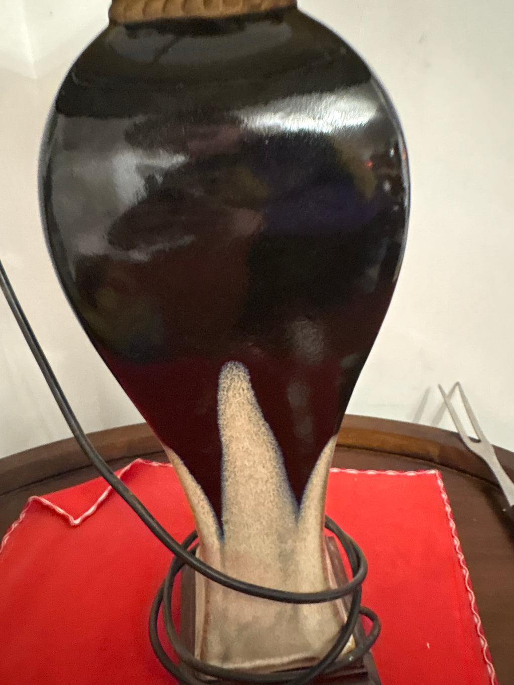 Close-up of ceramic lamp body showing glossy dark glaze and cream pointed decoration