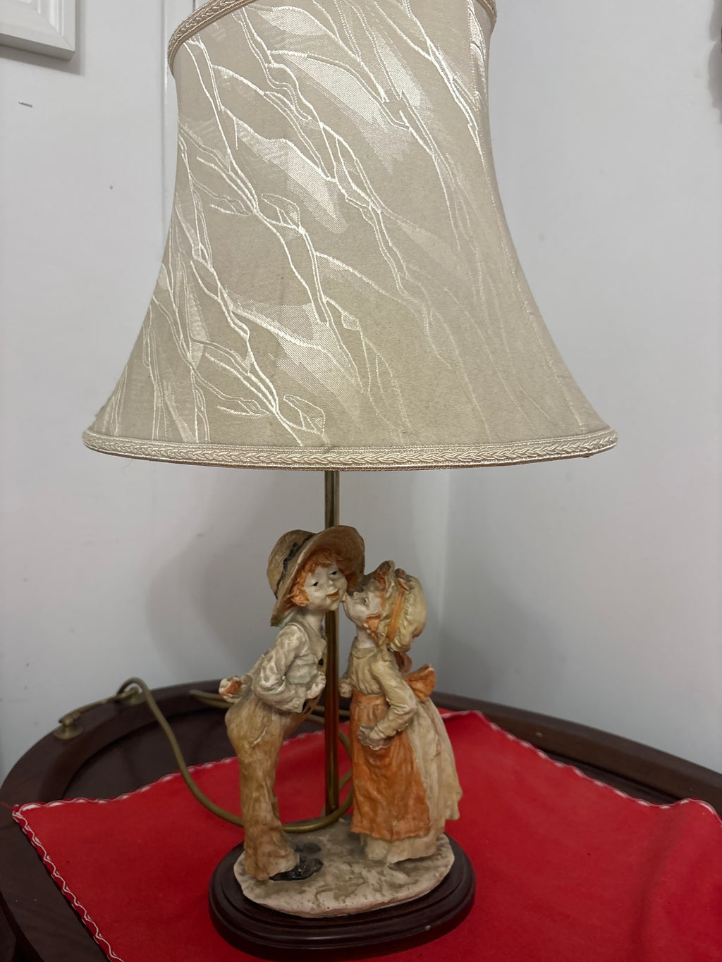 Shy Kiss figural table lamp with two children kissing beneath a cream patterned shade