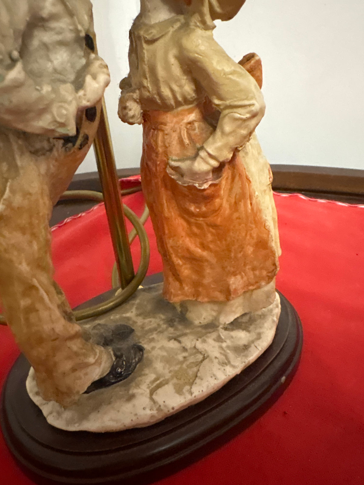 Close-up of the girl’s orange skirt, children’s feet and oval base on the figural lamp