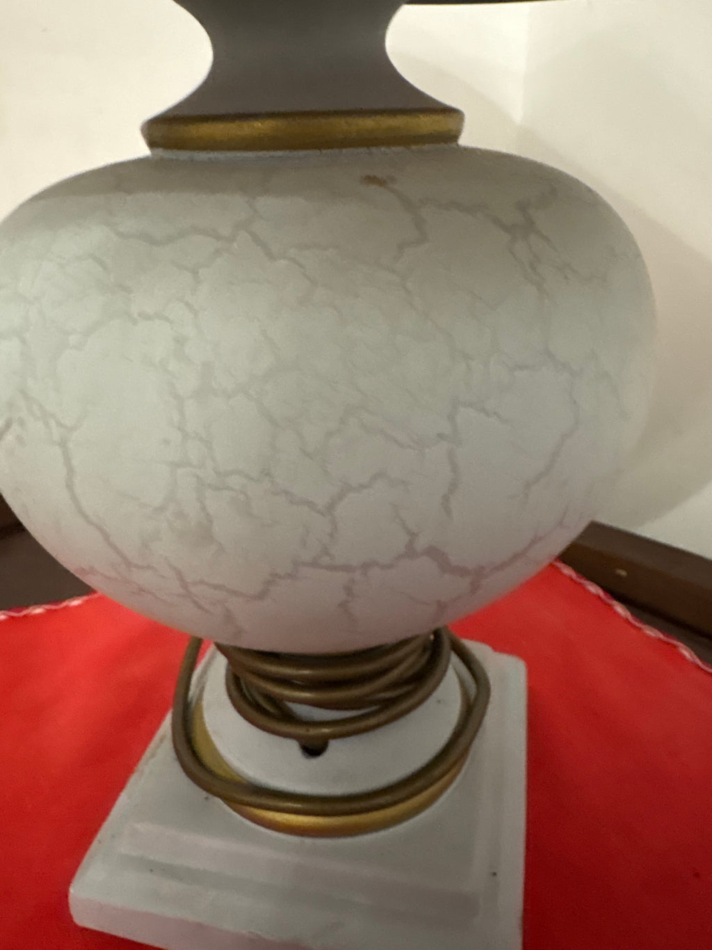 Close-up of round ceramic lamp body showing crackle glaze, gold-coloured trim and square base