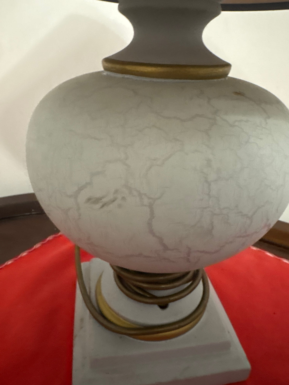 Front detail of pale crackle-glaze ceramic lamp body and its gold-coloured base rings