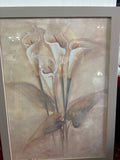 Framed floral picture of white calla lilies with long green stems and muted brown leaves.