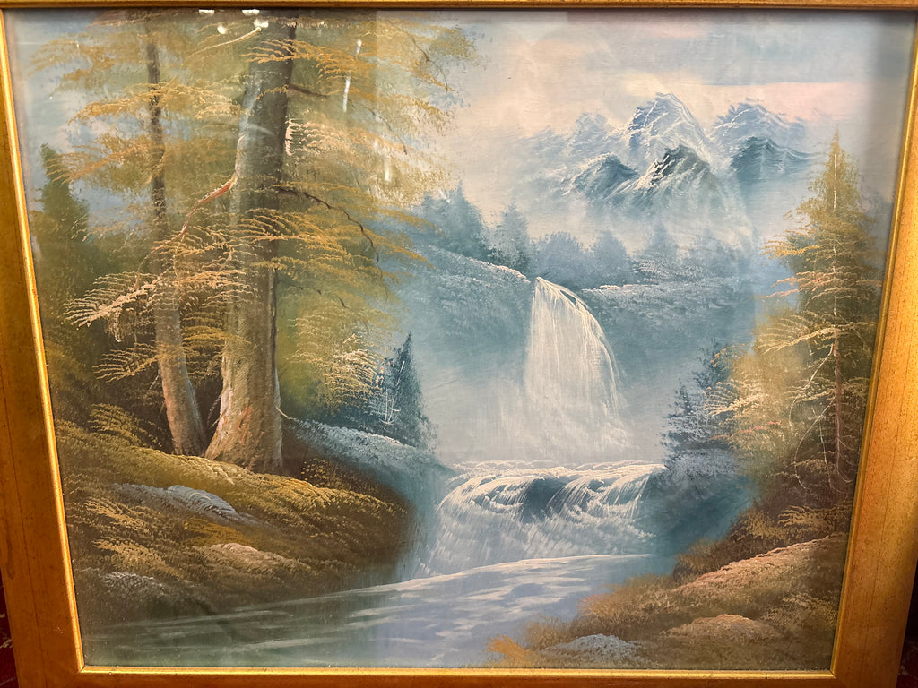 Framed mountain landscape with a cascading waterfall, snow-capped peaks and golden woodland beside a river.