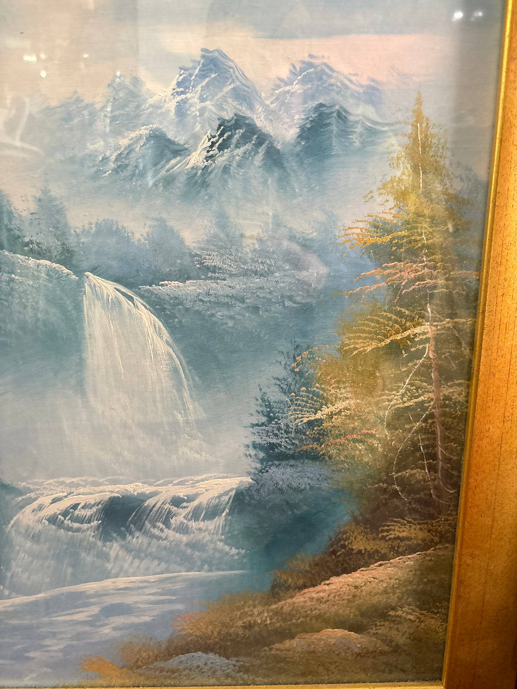 Right-side landscape detail showing snow-capped mountain peaks, a waterfall and golden trees along the riverbank.