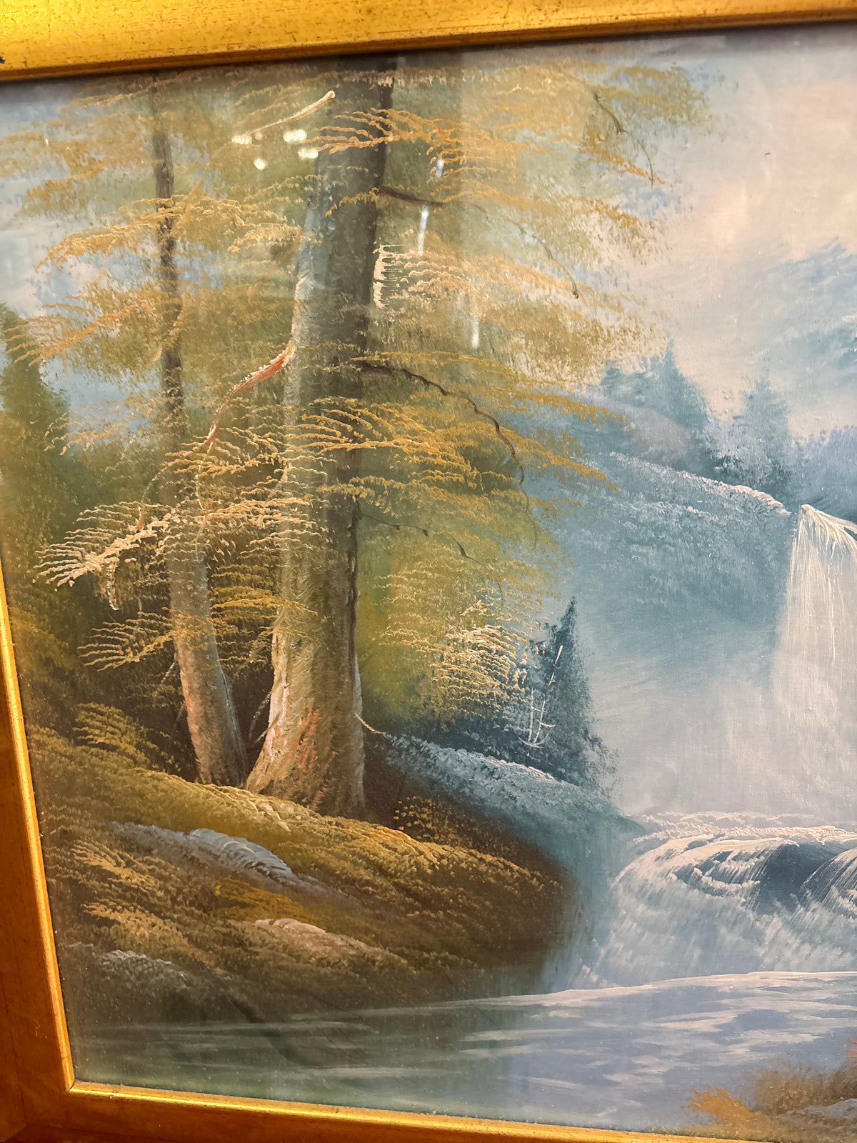Left-side landscape detail showing tall golden trees, a mossy riverbank and water cascading over rocks.