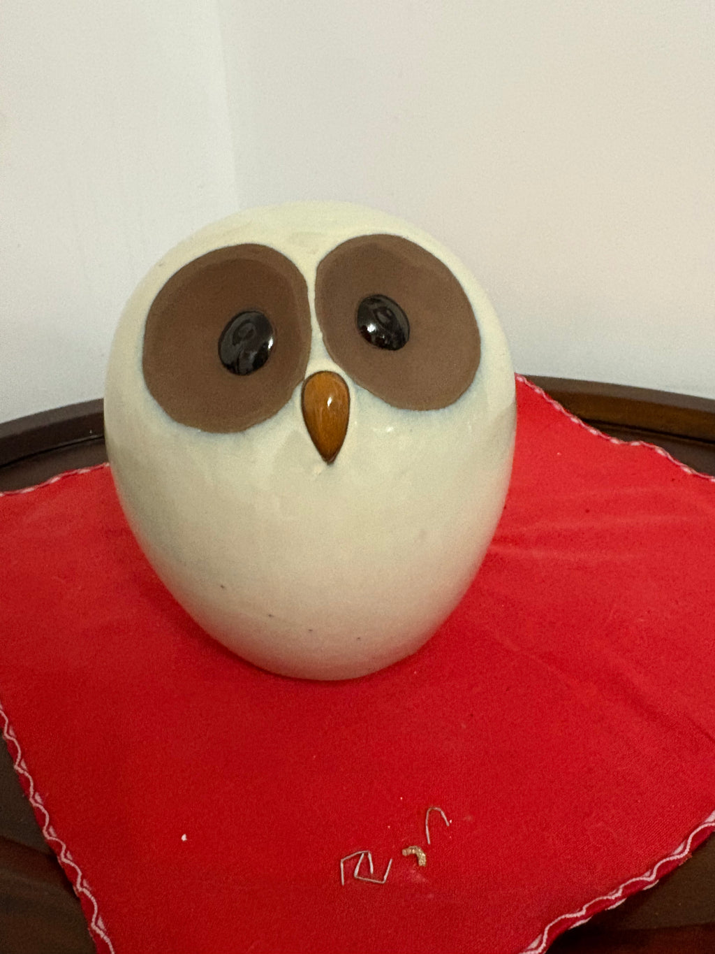 Full front view of a cream owl figurine with oversized brown eye patches, glossy black eyes and amber-coloured beak