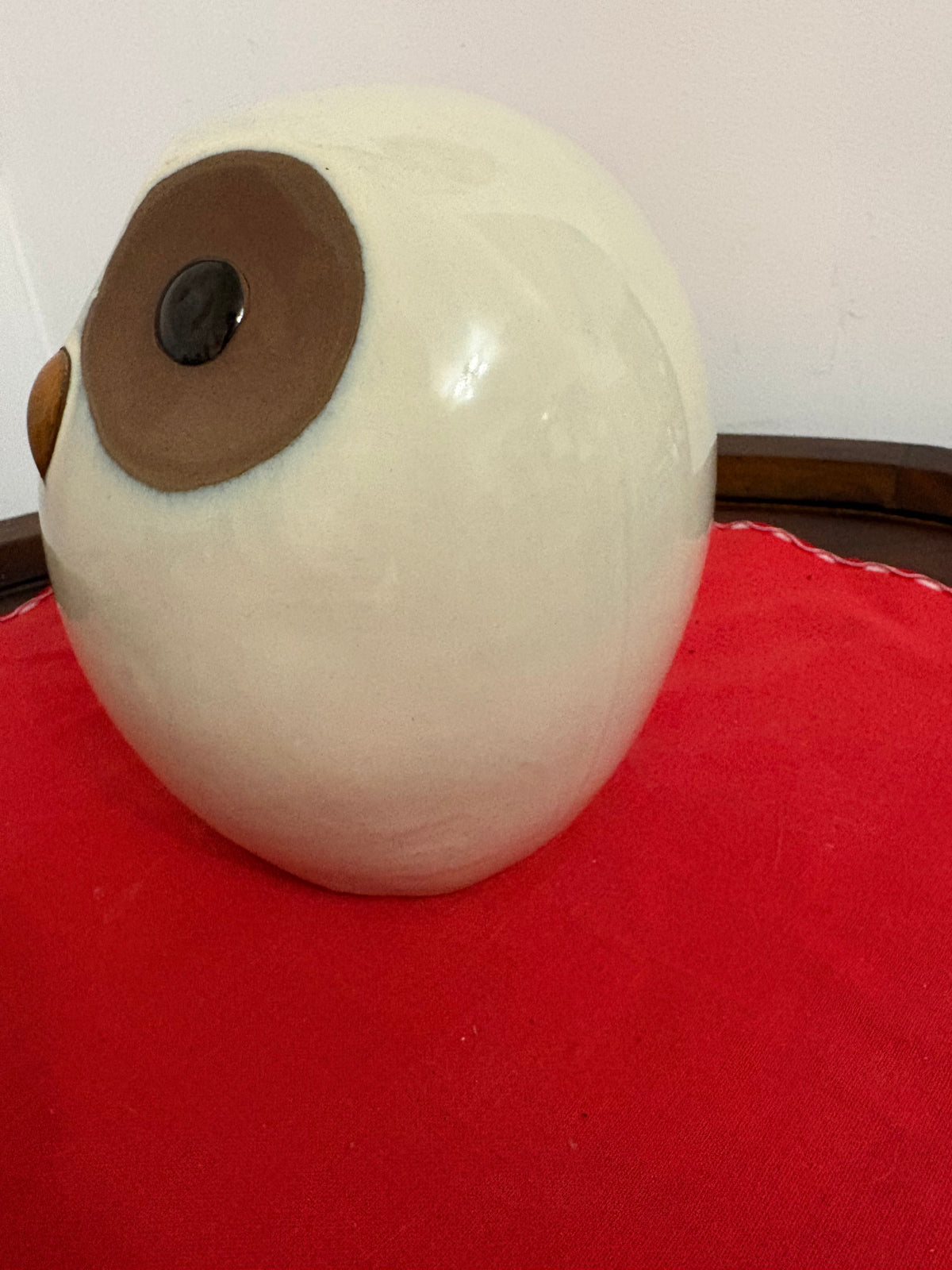 Opposite side view of the cream owl figurine showing its rounded body and brown eye patch