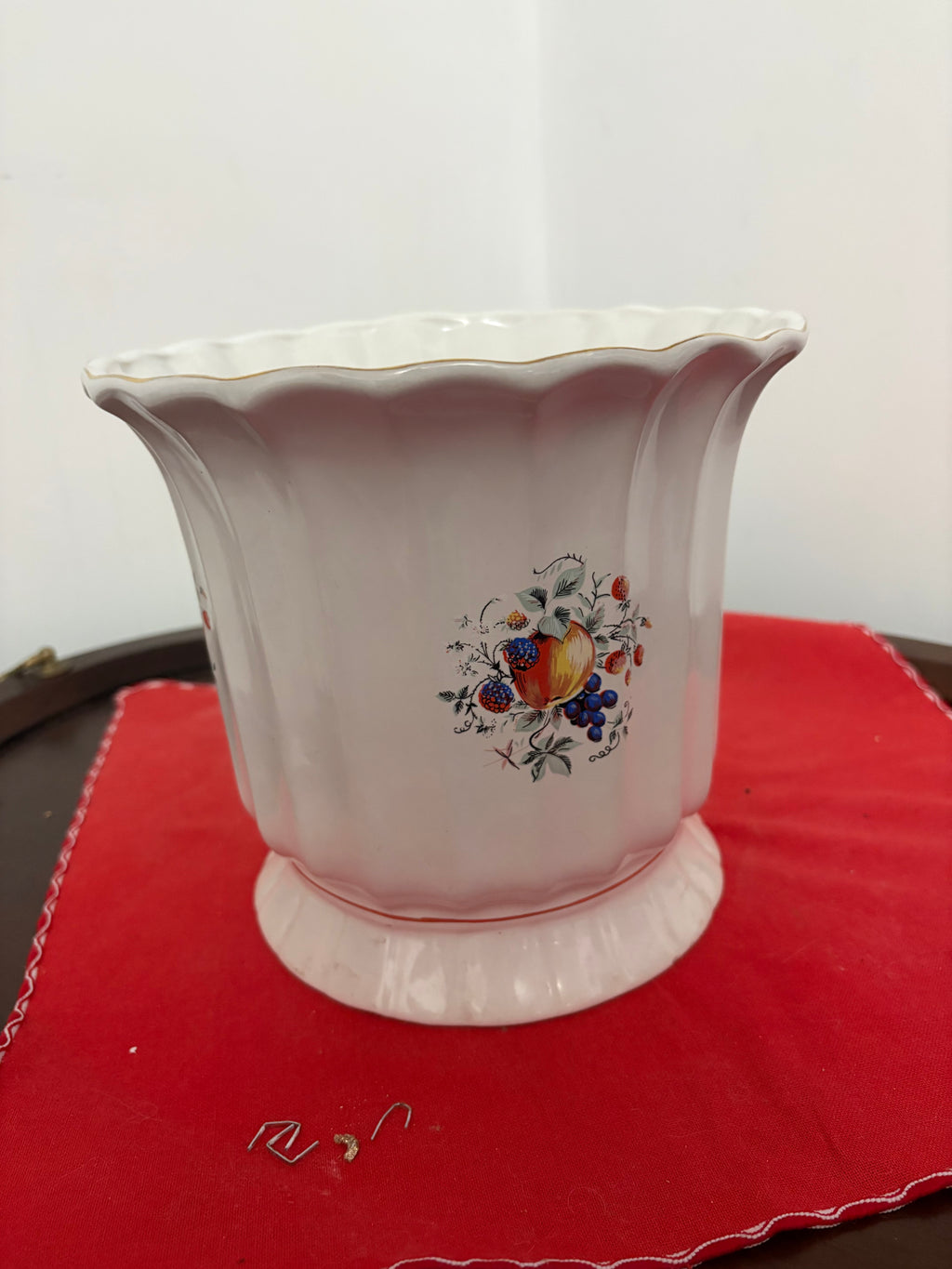 Front view of cream ceramic planter showing fruit motif, fluted body and scalloped rim