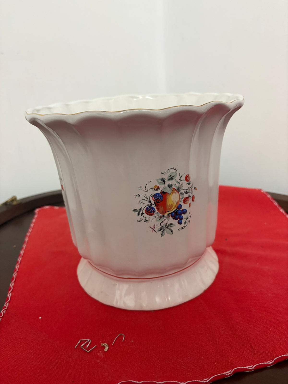 Front view of cream ceramic planter showing fruit motif, fluted body and scalloped rim