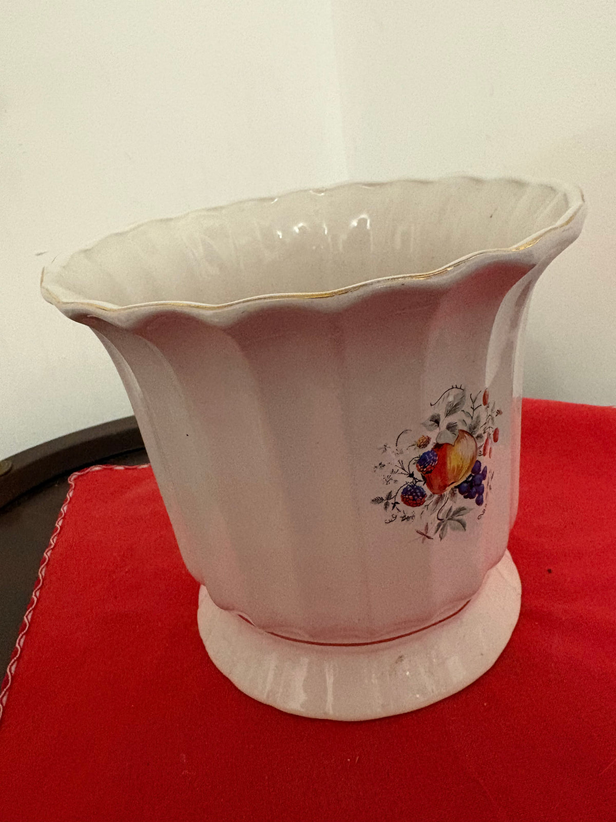 Angled view of cream fruit-decorated planter showing its open interior and flared scalloped rim