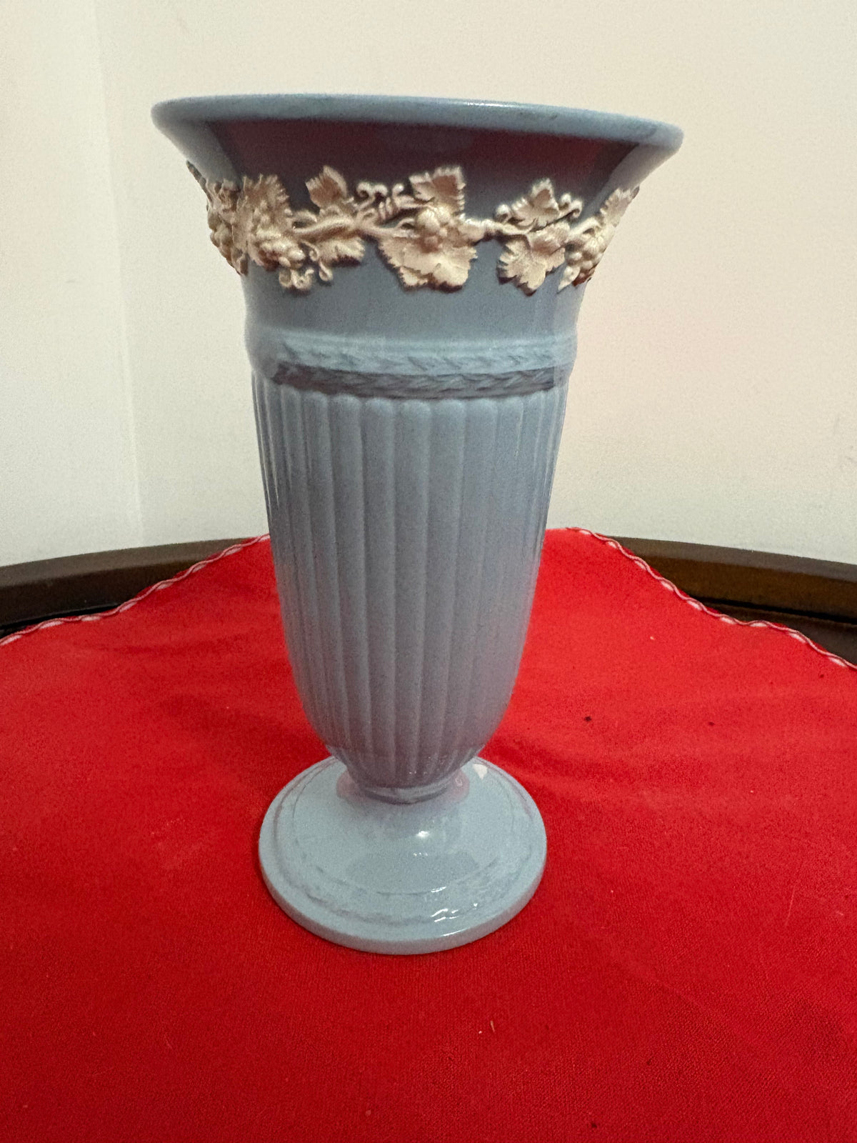 Blue-grey fluted trumpet vase with cream raised grapevine decoration beneath the flared rim