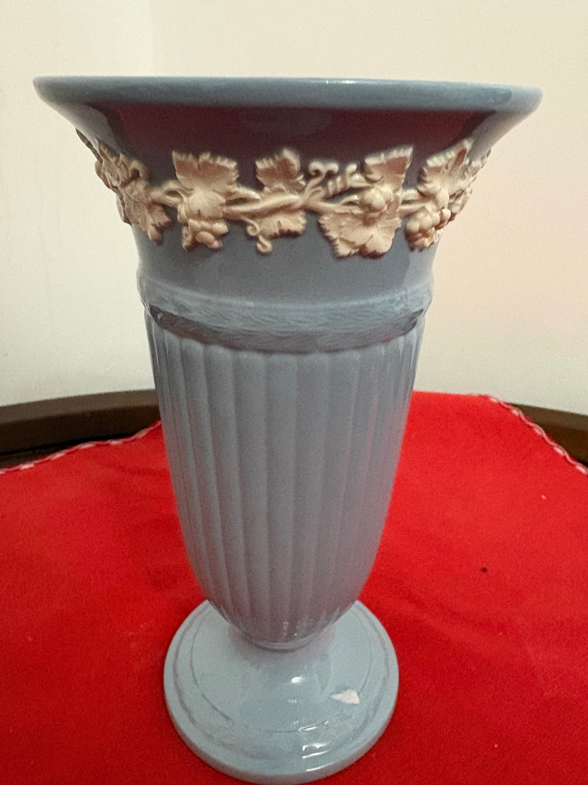 Full view of blue-grey pedestal vase showing vertical fluting and cream grapevine band