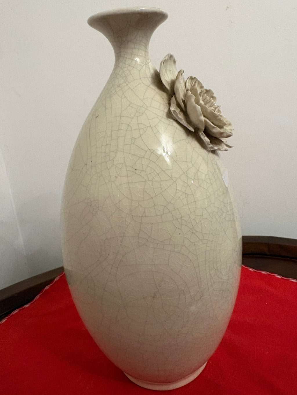Side view of off-white ceramic vase showing raised flower projecting from the shoulder