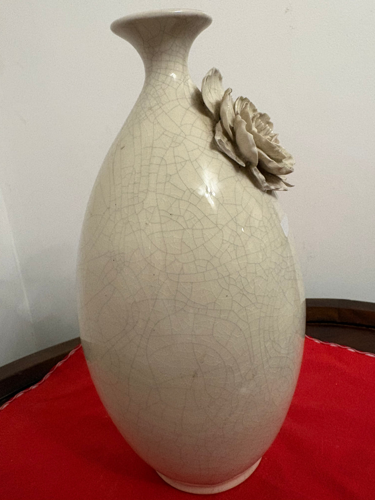 Side view of off-white ceramic vase showing raised flower projecting from the shoulder