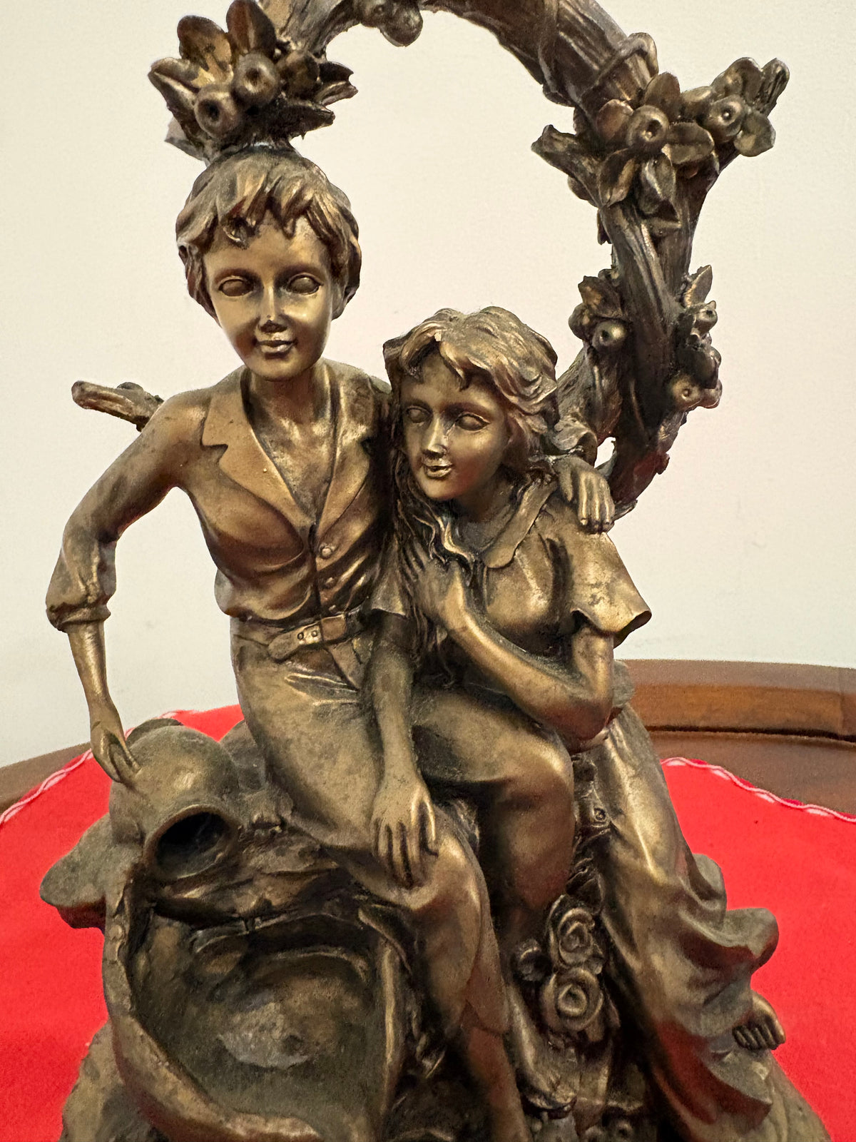 Close-up of the seated couple beneath the floral arch, showing their faces and the boy’s arm around the girl
