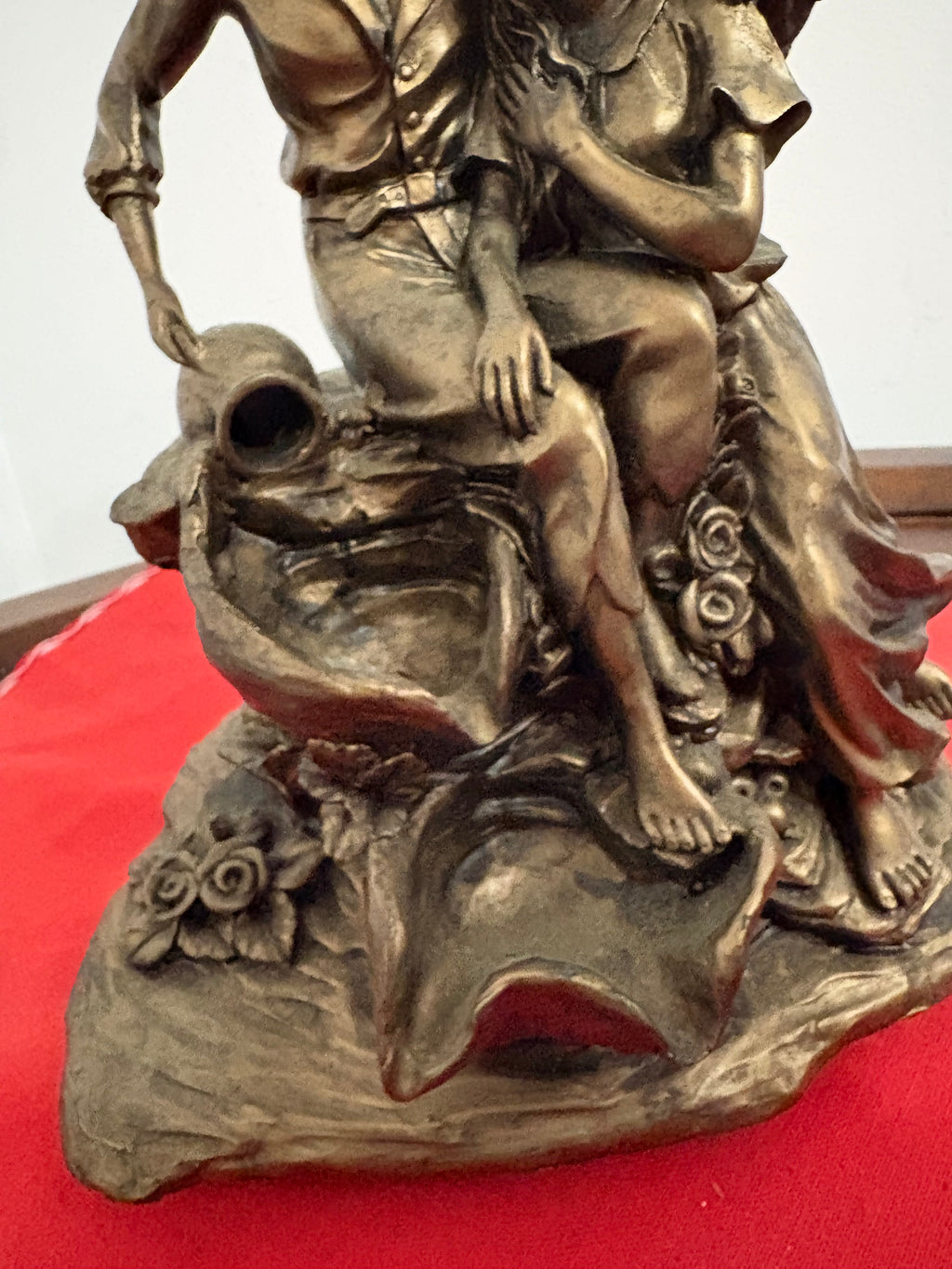 Close-up of cascading bowls, flowers and the boy’s legs on the bronze-coloured couple figurine