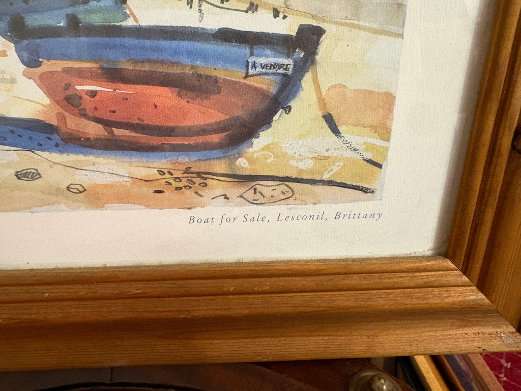 Lower-right detail of the boat print showing its title and wooden frame corner.